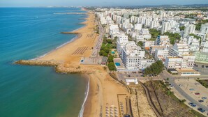 Vista aérea de una ciudad costera con playa, edificios y una carretera.