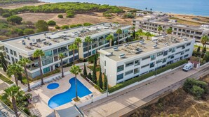 Un hotel moderno con piscina en la azotea, varios pisos y vistas al mar.