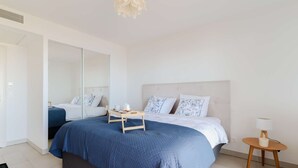A modern bedroom with a large bed, bedside tables, and a mirror.