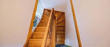 Una escalera de madera con barandilla de metal que conduce a una plataforma.