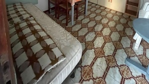 Quarto compacto com cama, mesa de jantar com cadeiras, cozinha compacta com armários e uma televisão.