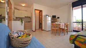 Un espace de vie compact comprenant une kitchenette, un coin repas et un balcon.