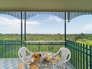 Un balcón con una mesa lista para el desayuno, con vistas a un paisaje verde y exuberante.