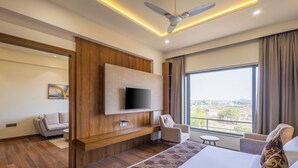Una habitación de hotel moderna con una cama grande, un televisor de pantalla plana montado en la pared, un sofá, una silla y una mesita.