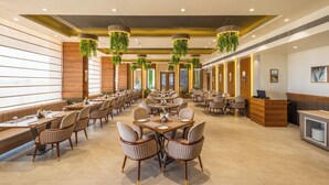 Un restaurante espacioso con techos altos, plantas colgantes y un diseño moderno.