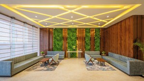 Un área de estar moderna con pared verde, paneles de madera y un diseño geométrico en el techo.