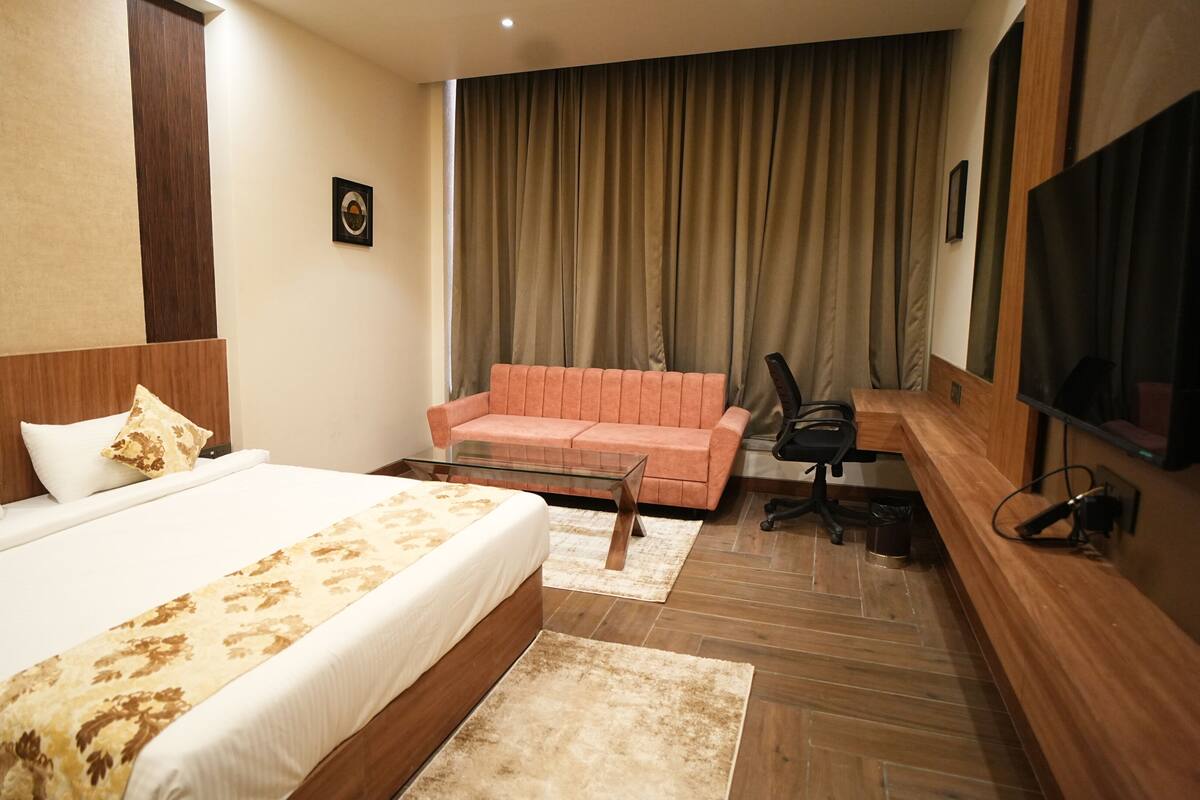Una habitación de hotel con una cama grande, un sofá, un escritorio y un televisor.