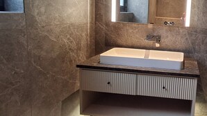 Een badkamer met een witte wasbak, een spiegel en een handdoekrek.