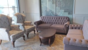 Een woonkamer met een gestoffeerde bank, fauteuils en een salontafel.