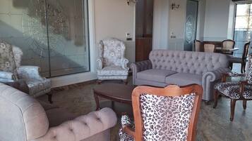 A spacious living room with a grey sofa, patterned armchairs, and a leopard print chair.