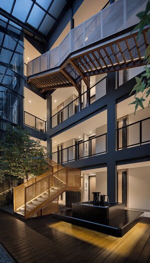A multi-level atrium with a central staircase, glass walls, and a seating area. - FULMAR Pasteur (Bandung)