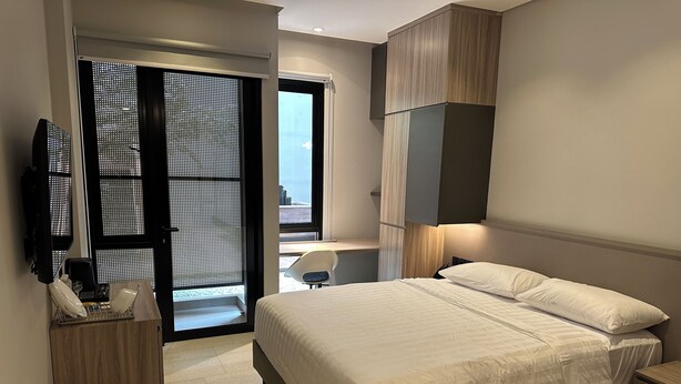 A modern hotel room with a large bed, a desk, and a TV. - Fulmar Pasteur (Bandung)