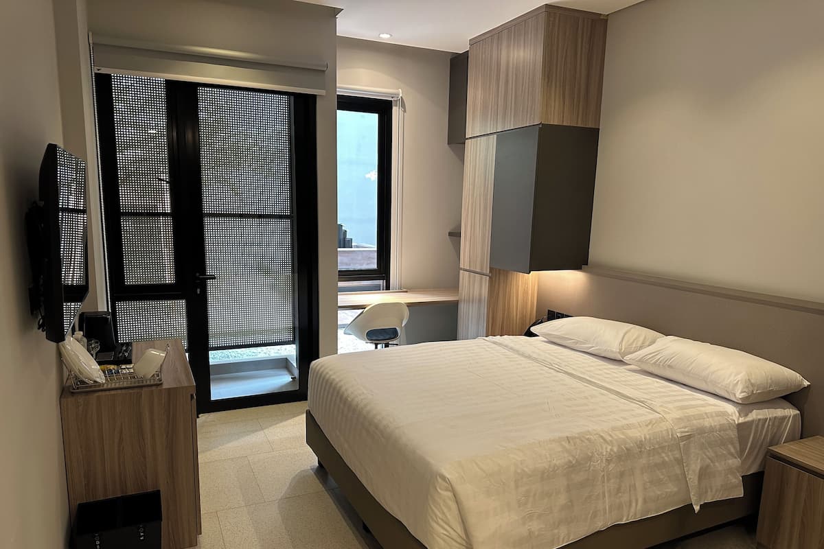 A modern hotel room with a large bed, a desk, and a TV.