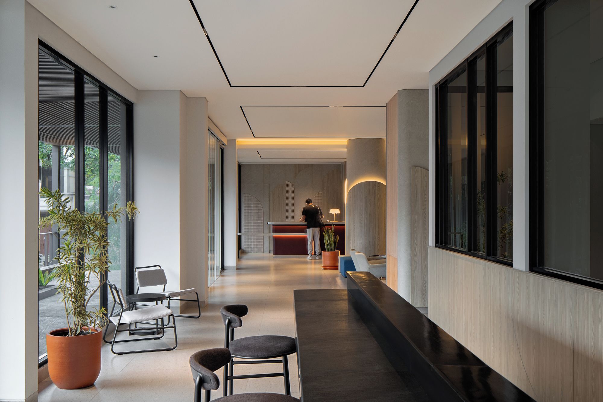 A modern hotel lobby with a reception desk, seating area, and large windows.