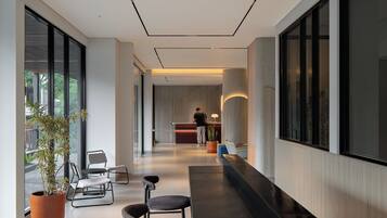 A modern hotel lobby with a reception desk, seating area, and large windows.