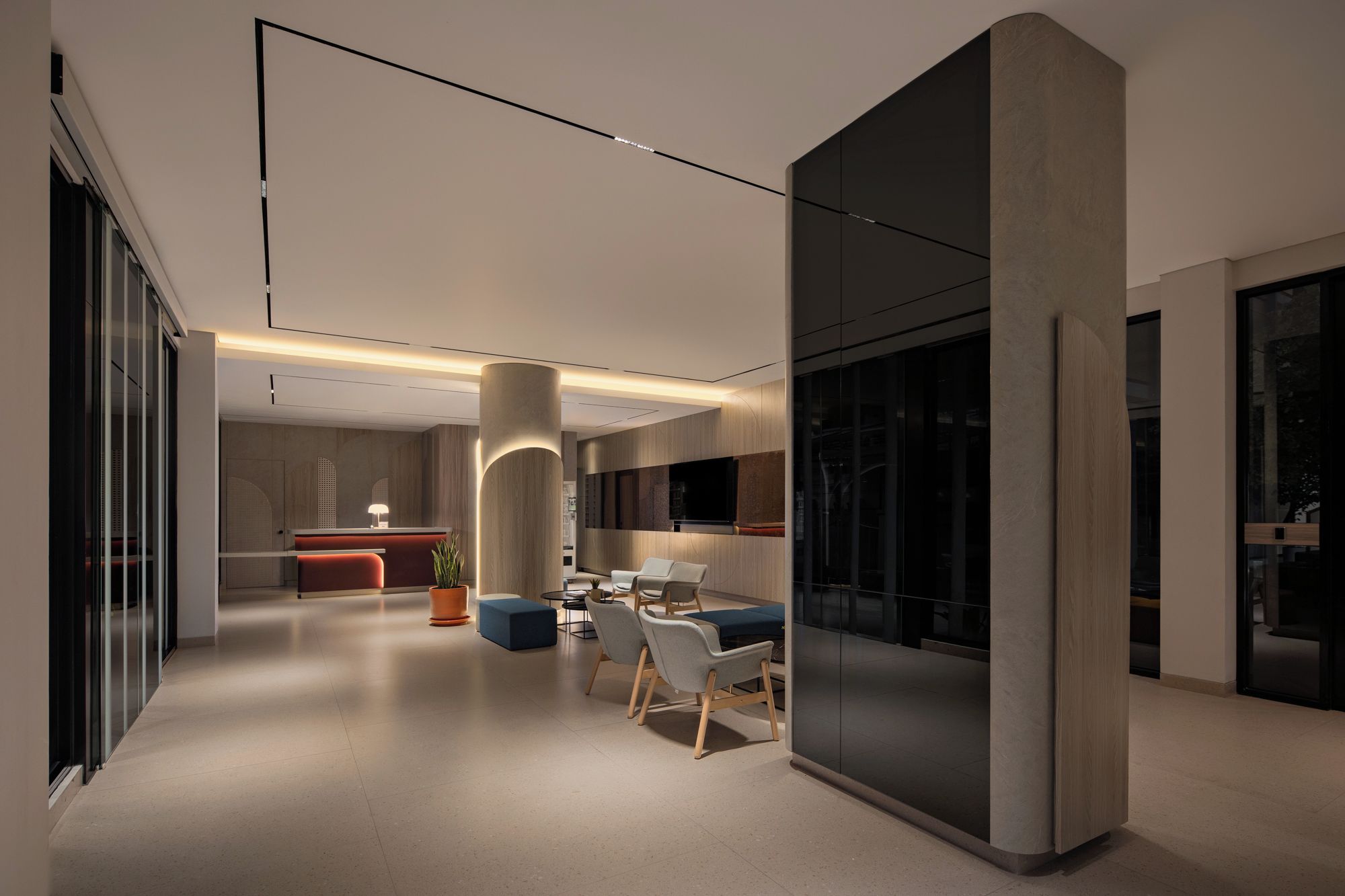 A modern interior with a reception desk, seating area, and a large window.