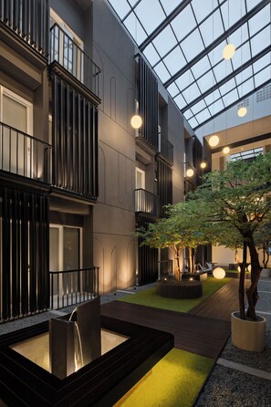 Un edificio moderno con un patio, una fuente de agua y un árbol.