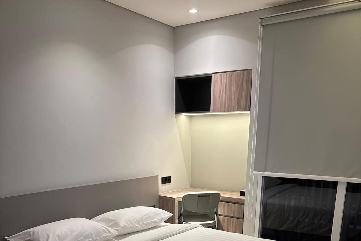 A modern bedroom with a large bed, a desk, and a chair.