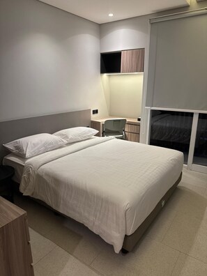 A modern bedroom with a large bed, a desk, and a chair. - Fulmar Pasteur (Bandung)