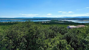 En vy över en sjö med omgivande grönska och några få byggnader i fjärran.