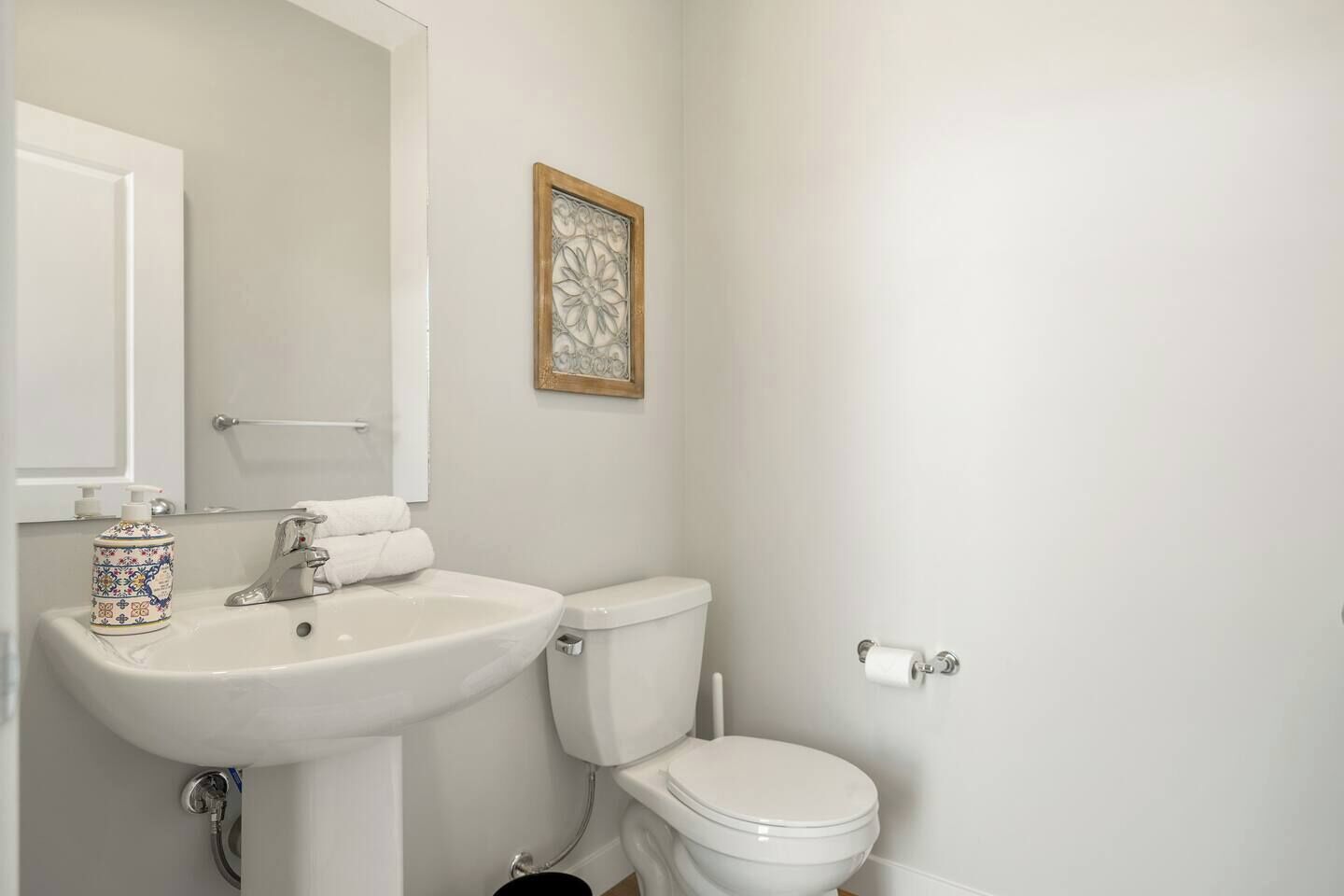 Een badkamer met een wit wastafel, toilet en een decoratief kunstwerk in een lijst aan de muur.