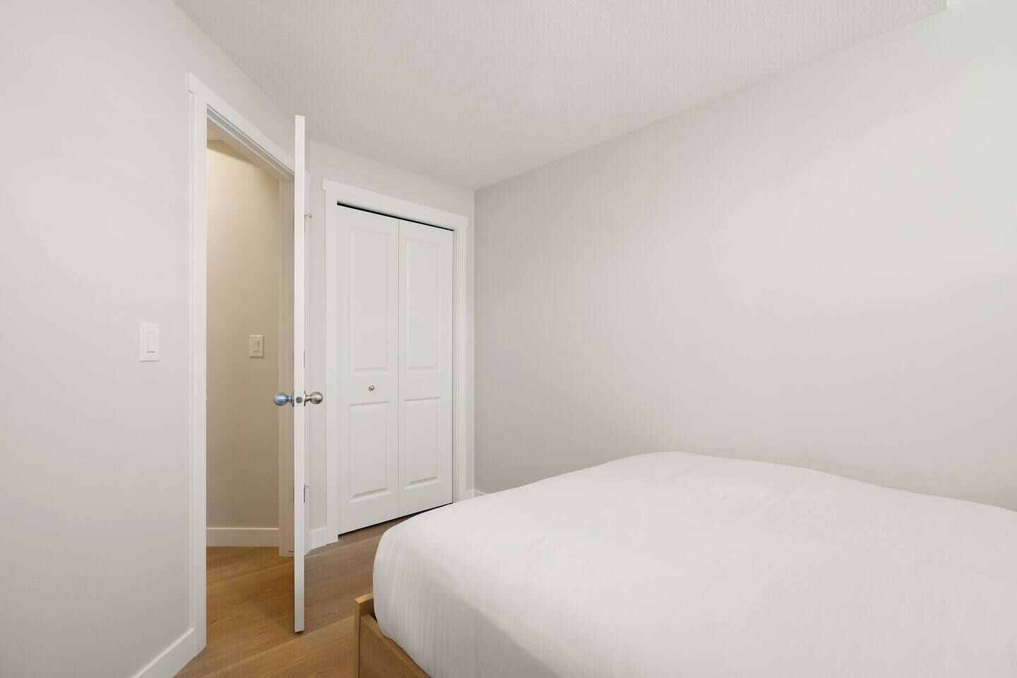 A bedroom with a bed, a door, and a light switch on the wall.