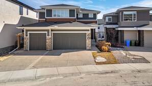 A residential area with modern houses, a garage, and a well-maintained lawn. - Bright Nature Escape 2BR Walkout Suite w/ Patio (Calgary)