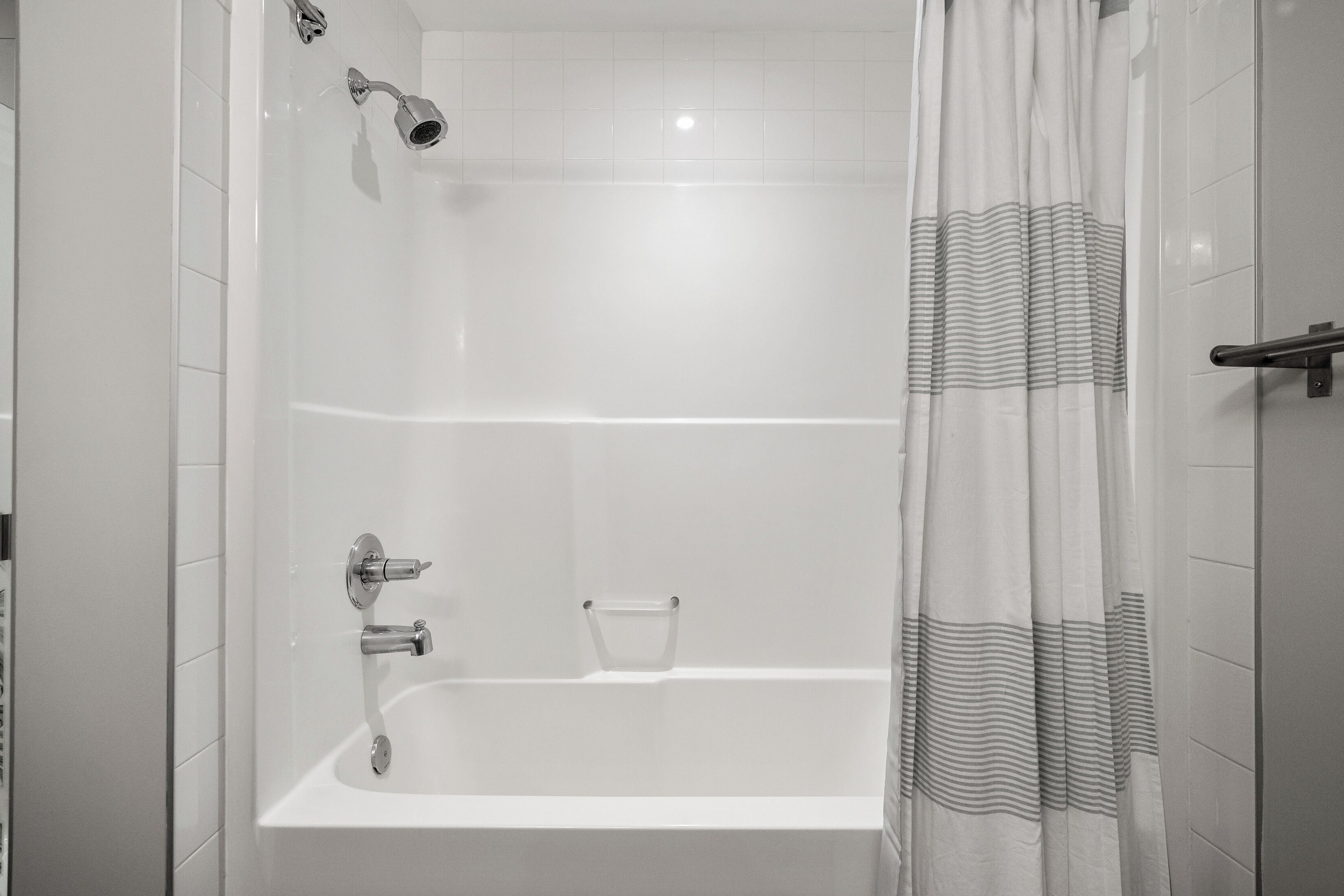 Een moderne badkamer met een badkuip, een douchekop en een glazen douchebak.