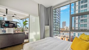 A modern hotel room with a large bed, a TV, and a city view.