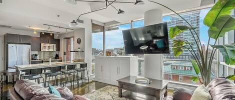 Una sala de estar moderna con un sofá de cuero, un televisor de pantalla plana y un amplio ventanal con vistas a la ciudad.