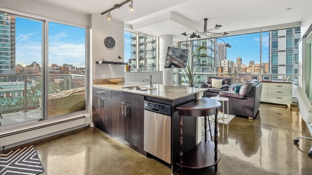 A modern kitchen with a dishwasher, a dining area with a sofa, and large windows offering a city view.