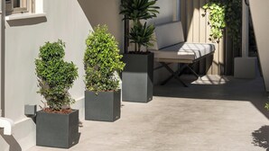 A modern outdoor seating area with a bench and potted plants. - Pi Suite Project Smart Living (Chania)