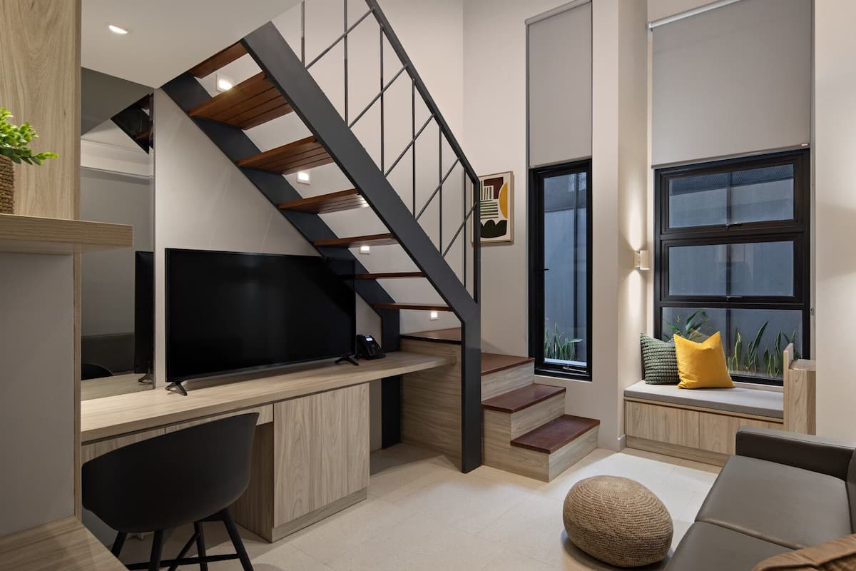 A modern interior with a staircase, a desk, a chair, a sofa, and a window with a view.