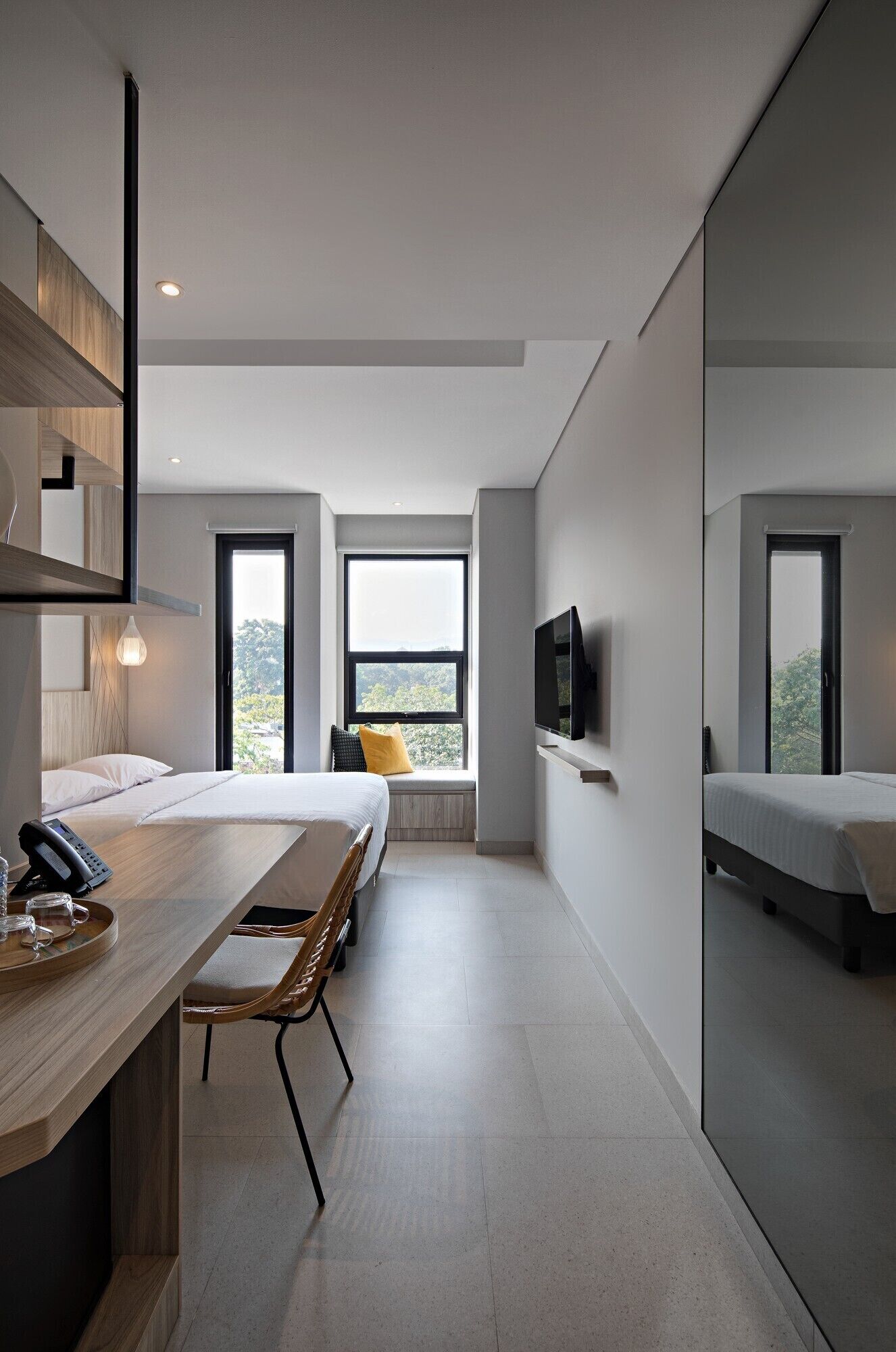 Une chambre d’hôtel moderne équipée d’un lit, d’une table de chevet et d’un téléviseur fixé au mur.