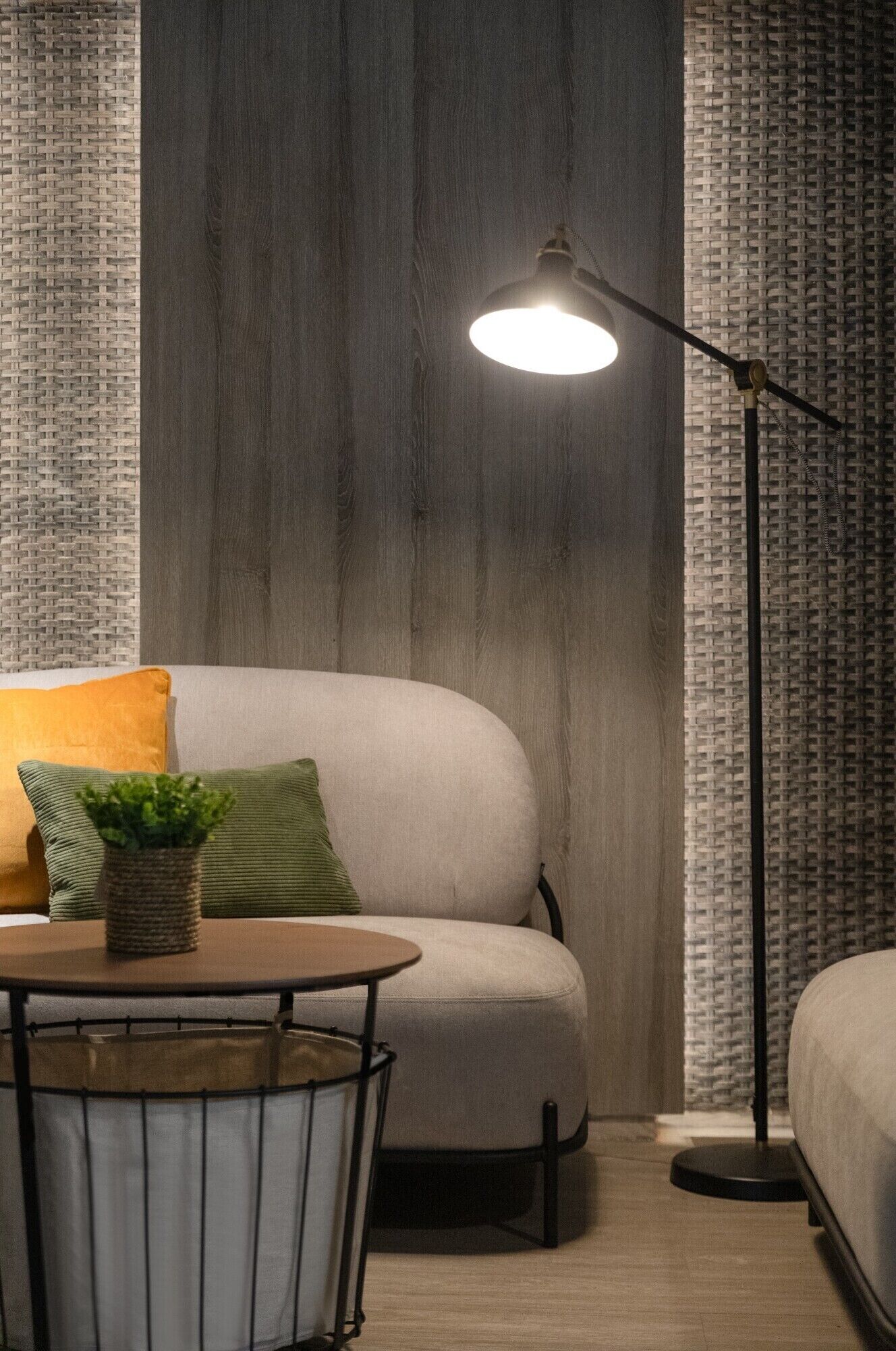 A cozy room with a sofa, a small round table with a plant, and a floor lamp.