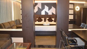 A hotel room with a bed, a sofa, a desk, and a chair. - Hotel Free Birds  (Tiruchirappalli)