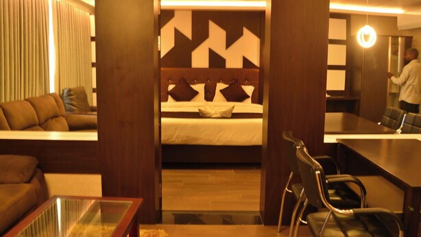A hotel room with a bed, a sofa, a desk, and a chair. - Hotel Free Birds  (Tiruchirappalli)