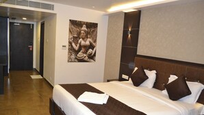 A hotel room with a large bed, a headboard, and a wall-mounted artwork. - Hotel Free Birds  (Tiruchirappalli)