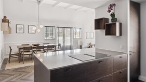 Een moderne keuken met een centraal eiland, ingebouwde kasten en hangende verlichting.