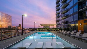 A rooftop pool with lounge chairs and a 'No Diving' sign, surrounded by modern buildings and a sunset sky. - High-rise Apt Raleigh Free Parking Sunset View 1 (Raleigh)