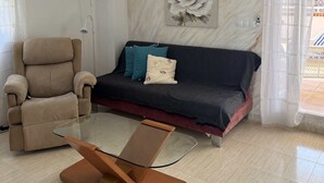 Un salon avec un canapé, un fauteuil et une table basse en verre.