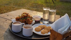 A tray with food and drinks on an outdoor table with a scenic view. - Vanah Villa And Resort (Mawal)