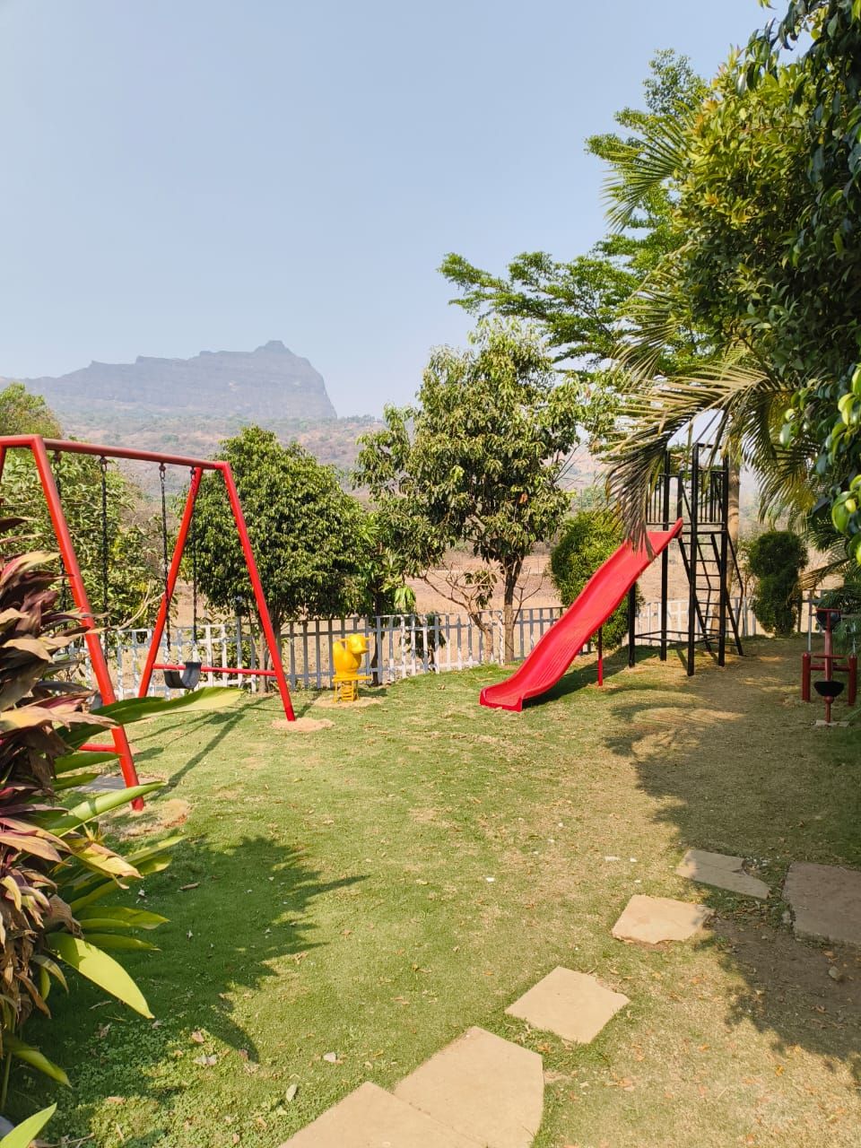 Ein Spielplatz mit Schaukeln, einer Rutsche und einer Kletterkonstruktion.