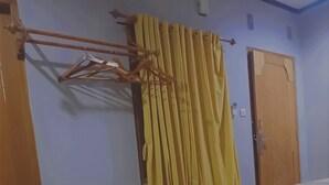 Une pièce comprenant un lit, une armoire en bois, un rideau et un climatiseur fixé au mur.