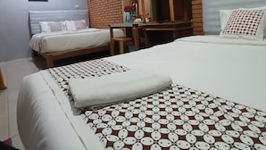Une chambre d’hôtel avec deux lits, une tête de lit en bois, un mur en briques et un téléviseur fixé au mur.