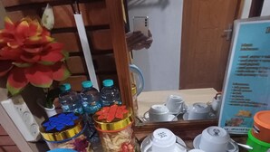 Un coin cuisine équipé d’une bouilloire, de bouteilles d’eau, d’une machine à café et d’un tableau affichant le menu.