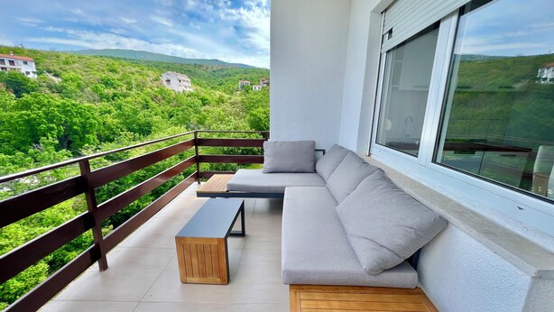 A balcony with a wooden bench, a grey sofa, and a small table. - Apartman Velly  (Jadranovo)