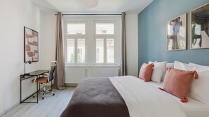 Ein modernes Hotelzimmer mit einem großen Bett, einem Schreibtisch und Blick durch große Fenster nach draußen.