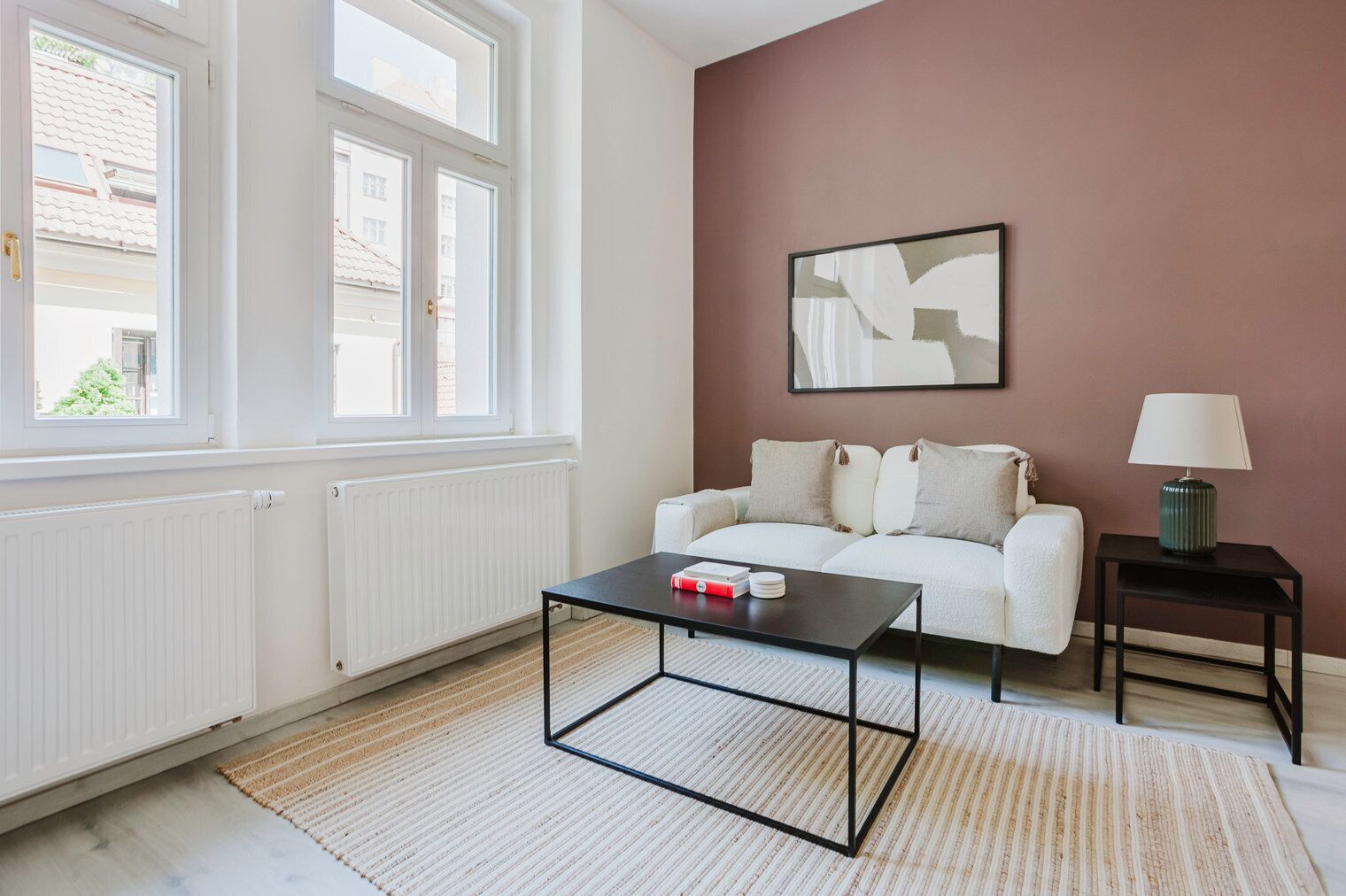 Un salon moderne avec un canapé blanc, une table basse noire et une table d’appoint avec une lampe.