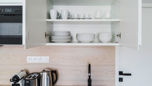 A kitchen with white cabinets, a microwave, a kettle, and a toaster. - Blueground | Prague 3, close to offices & mall (PRG-20) (Prague)